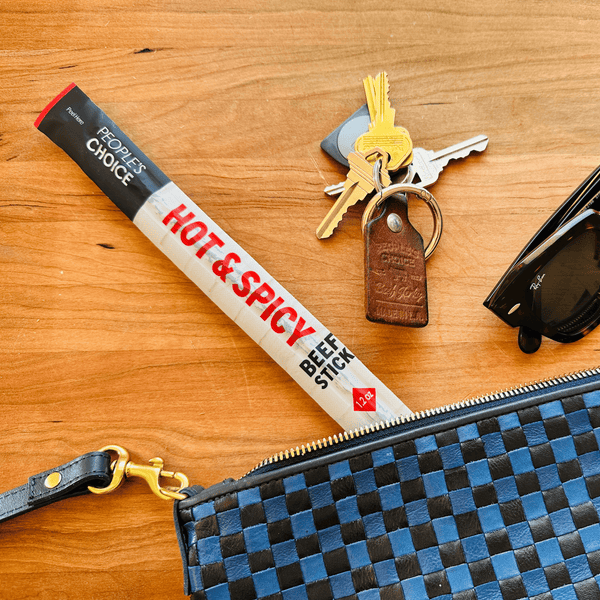 Hot and spicy beef stick on a table with a purse, keys, and sunglasses. 