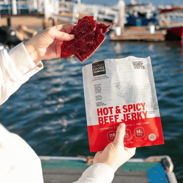 Hot & Spicy Beef Jerky package held by a person with a waterfront background