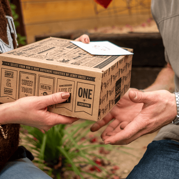 A man and woman sharing a beef jerky gift box. 
