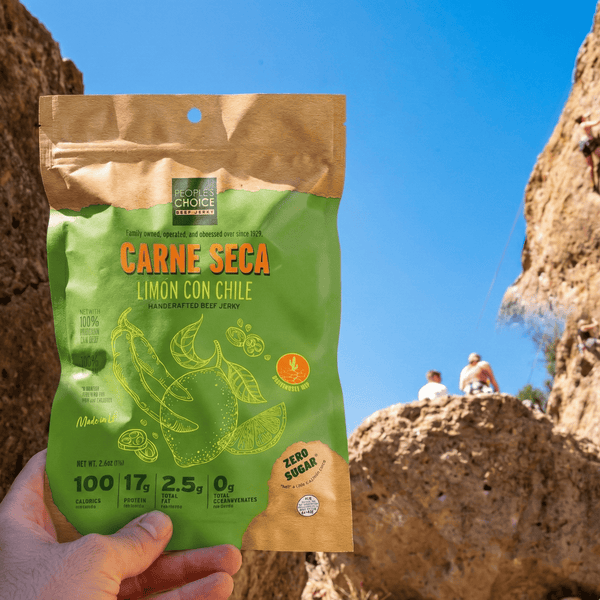 Hand holding a package of Limon Con Chile beef jerky in the desert canyon 