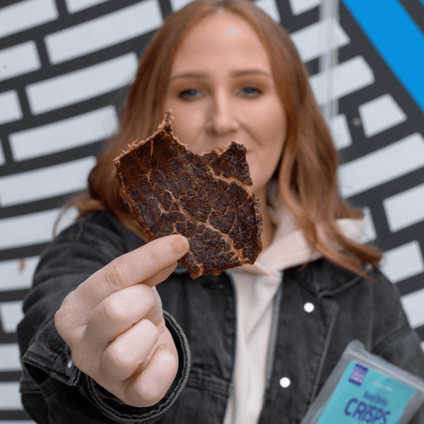 Woman holding a beef jerky crisp. 