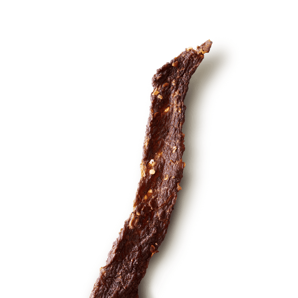 Free floating piece of Old Fashioned Hot & Spicy beef jerky on a plain background