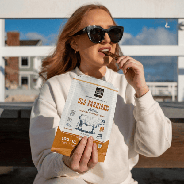 Woman eating a bag of Old Fashioned beef jerky outdoors 