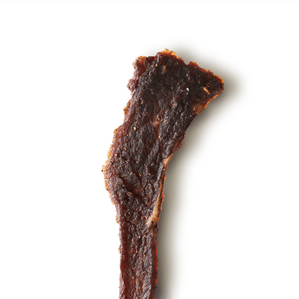 Close-up of a textured, beef jerky piece on a transparent background
