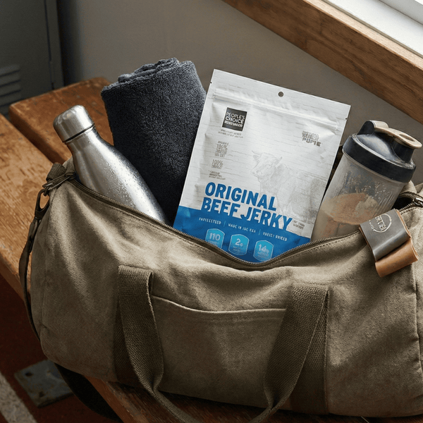 Beige duffel bag with beef jerky, water bottle, and other items on a wooden bench.