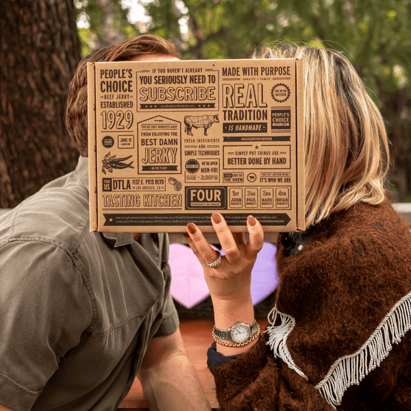 A man and woman holding a beef jerky gift box. 