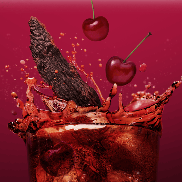 Glass of cherry cola soda with chocolate and cherries and a piece of beef jerky on a red background