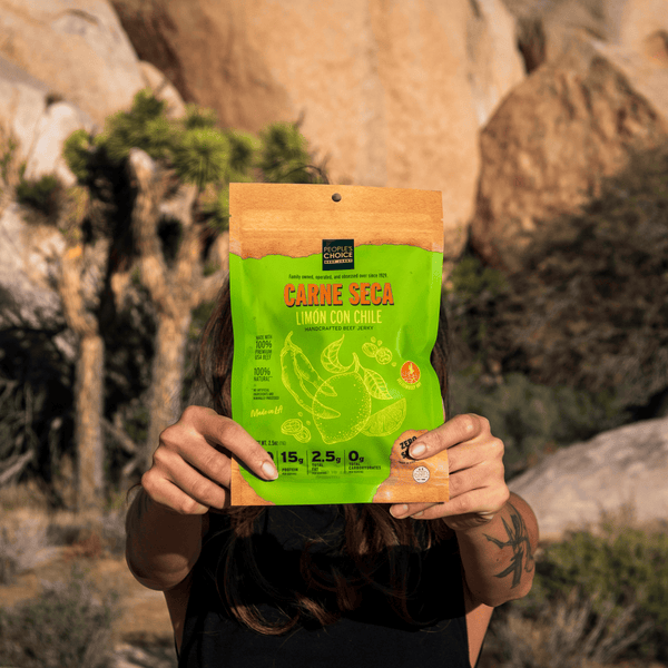 Woman holding a package of Limon Con Chile Beef Jerky in the desert 