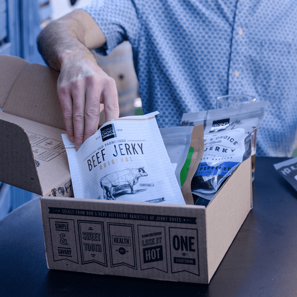 A man reaching into an opened bag of beef jerky. 