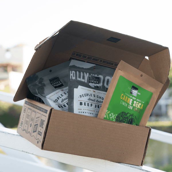Jerky Box that's slightly open with jerky packages in it on a ledge. 