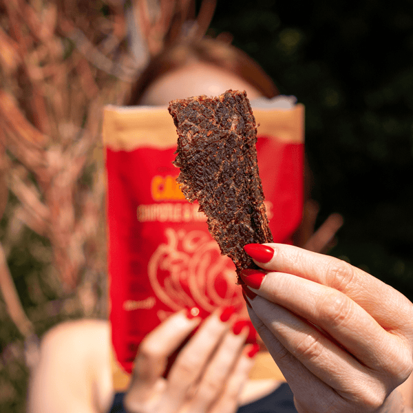 Someone holding a piece of Carne Seca Chipotle and Roasted Garlic Beef Jerky