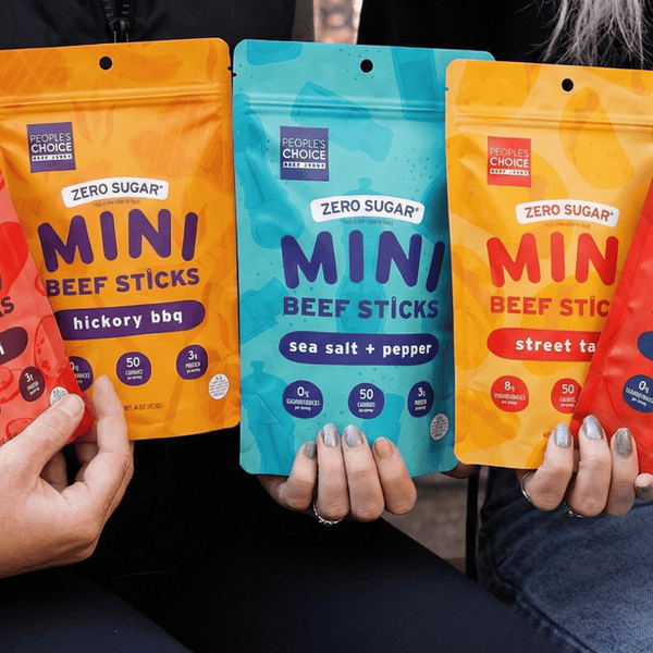 Four people holding packages of different flavors of mini beef sticks.